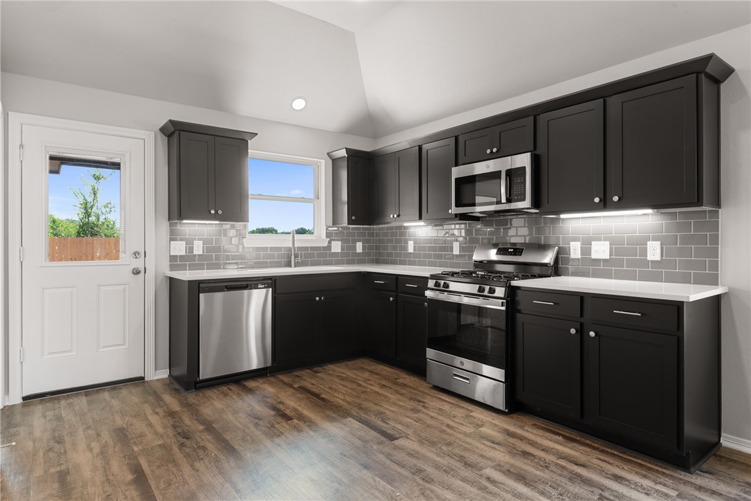 2869 Messenger Way Bryan, TX 77803 - Photo 12 of 23 a kitchen with stainless steel appliances granite countertop a stove a sink dishwasher a microwave oven and a refrigerator with wooden cabinets