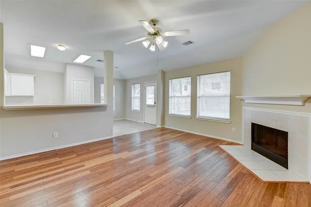 an empty room with wooden floor fireplace and windows