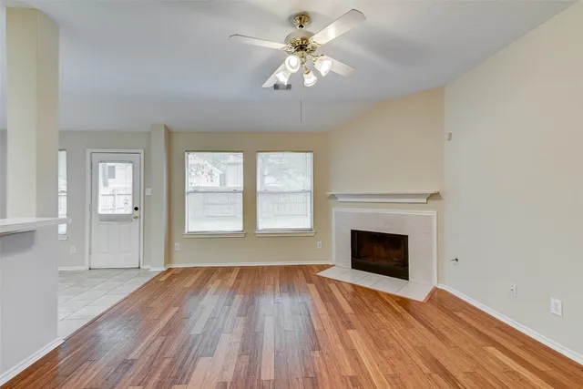 a view of an empty room with window and wooden floor