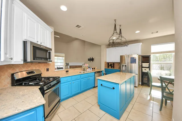 a large kitchen with stainless steel appliances granite countertop a stove refrigerator and a sink