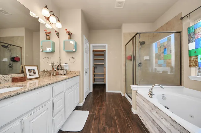a bathroom with a granite countertop bathtub a double vanity sink a vanity and a large mirror