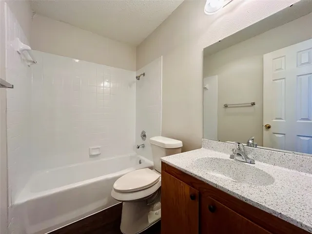 a bathroom with a granite countertop sink a toilet and bathtub