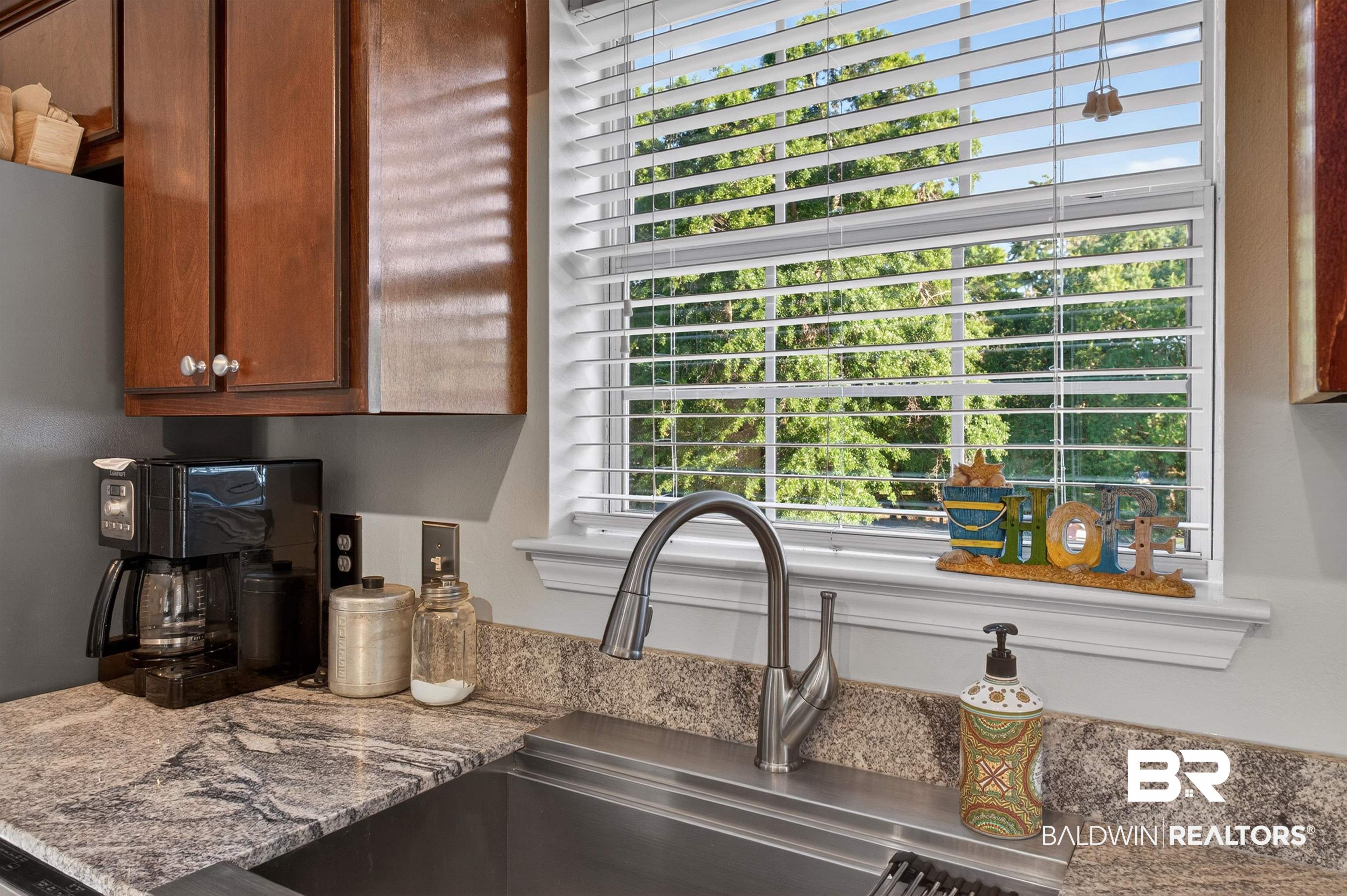 9624 North Bay Street Foley, AL 36535 - Photo 15 of 59 Kitchen featuring wood cabinetry, a stainless steel sink, and stone-finish countertops