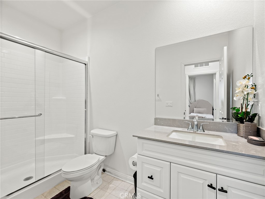 11520 Ferro Street Victorville, CA 92392 - Photo 16 of 40 a bathroom with a granite countertop sink a toilet a mirror and shower
