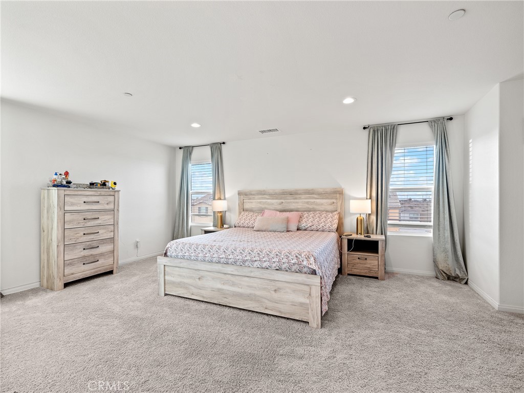 11520 Ferro Street Victorville, CA 92392 - Photo 19 of 40 a spacious bedroom with a bed a dresser and a couch