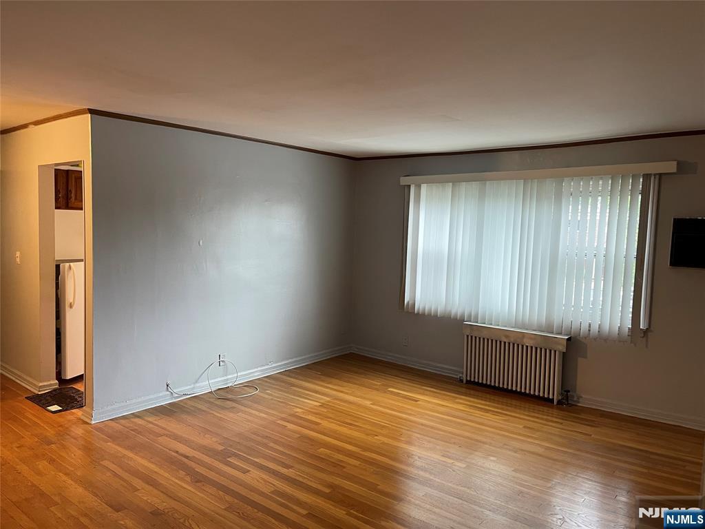 245 Passaic Avenue, Unit B4 Passaic, NJ 07055 - Photo 4 of 13 an empty room with wooden floor and windows