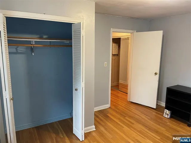 a view of a hallway with wooden floor and closet