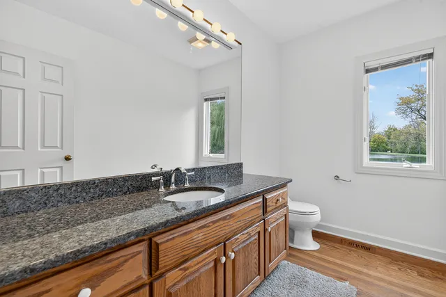 a bath room with a granite countertop toilet sink and mirror
