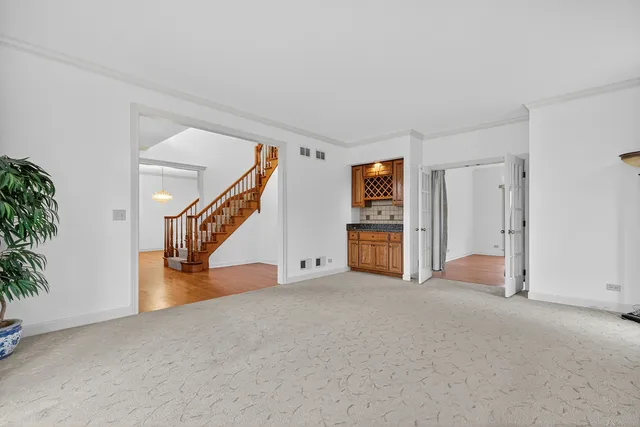 a view of an empty room with stairs and a living room