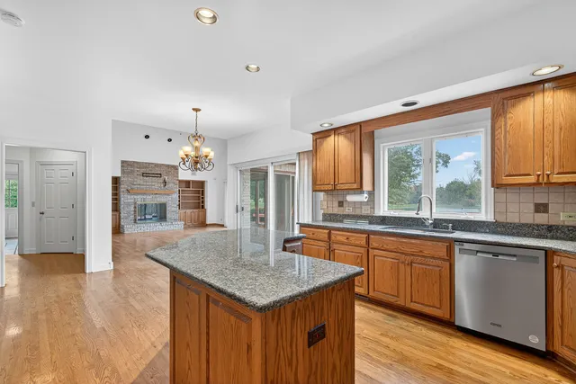a kitchen with granite countertop center island wooden floor and stainless steel appliances