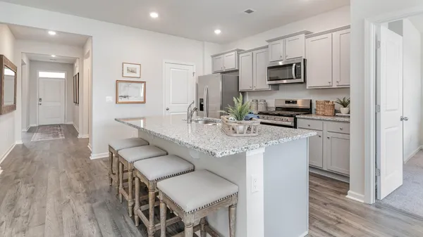 a kitchen with kitchen island granite countertop a sink a stove cabinets and wooden floor