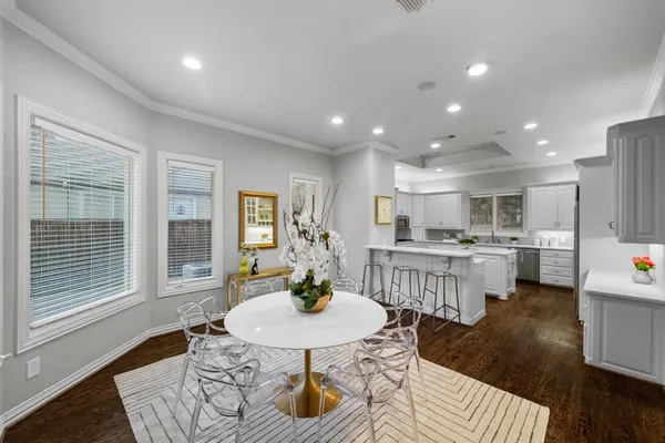 a kitchen with a dining table wooden floor and stainless steel appliances