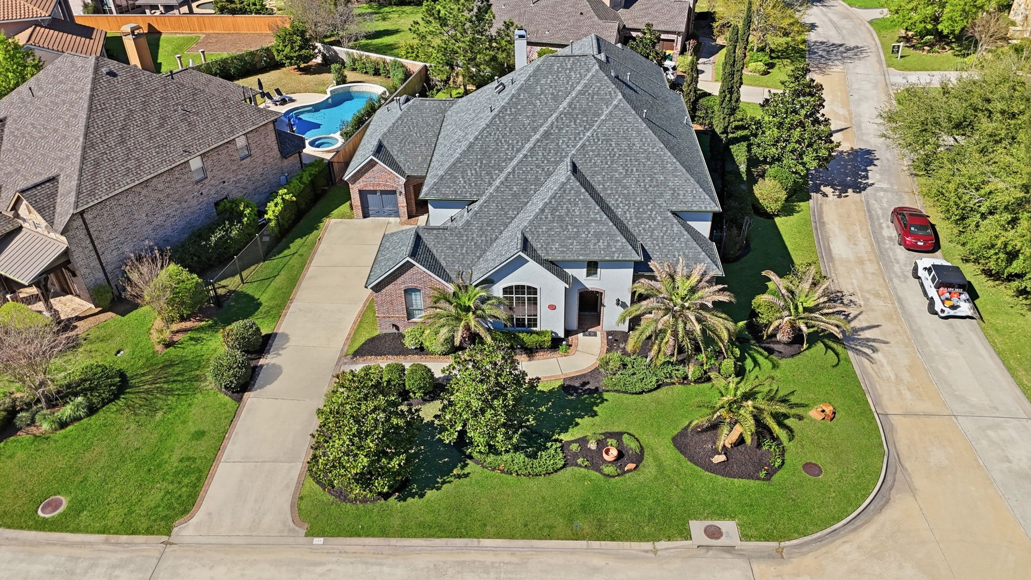 223 South Bauer Point Circle Spring, TX 77389 - Photo 39 of 50 This aerial view shows a spacious, well-maintained home on a corner lot with a manicured lawn and lush landscaping. The property features a long driveway, a two-car garage, and a backyard with a pool, offering a private oasis for relaxation.
