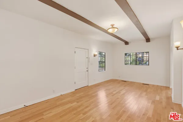 an empty room with wooden floor staircase and windows