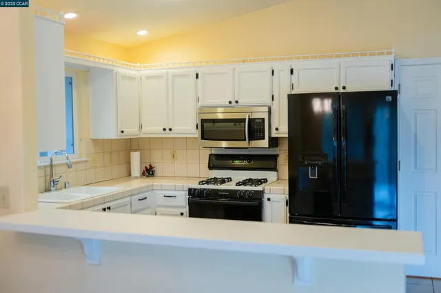 a kitchen with granite countertop a refrigerator and a stove top oven