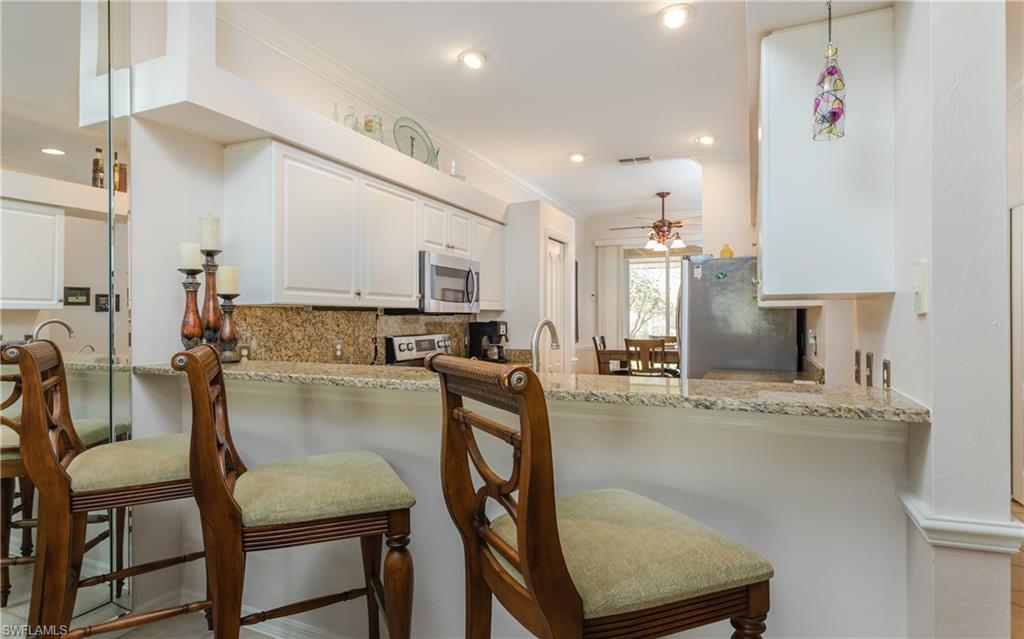21468 Knighton Run Estero, FL 33928 - Photo 6 of 21 a kitchen with kitchen island granite countertop a table chairs sink and cabinets