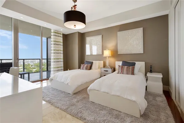 a bedroom with two beds and large windows