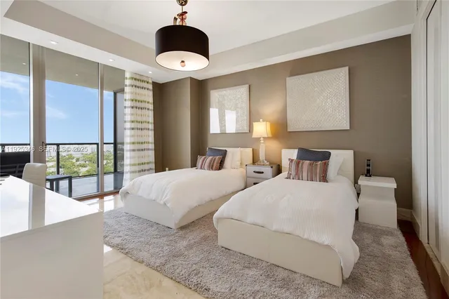 a bedroom with two beds and large windows