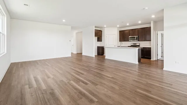 a view of kitchen with kitchen island granite countertop stainless steel appliances refrigerator sink and cabinets