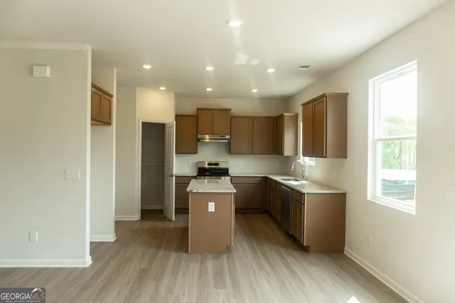 a kitchen with kitchen island wooden floors appliances and cabinets