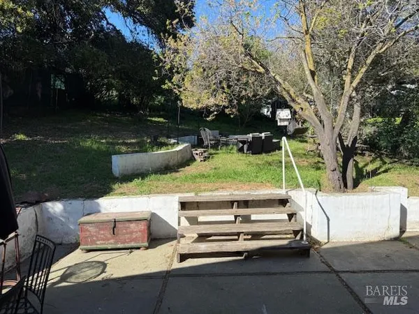 a view of a patio with table and chairs and a large tree