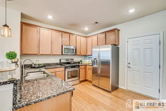 a kitchen with stainless steel appliances granite countertop a refrigerator sink and stove