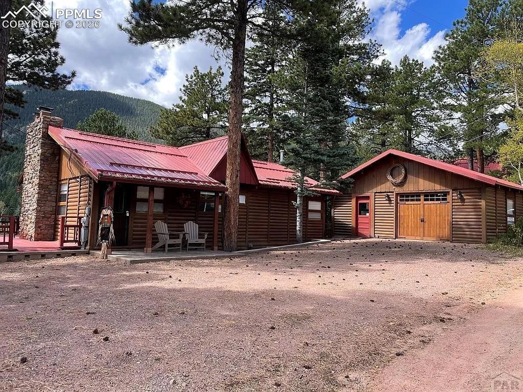 121 St Charles Drive Rye, CO 81069 - Photo 1 of 22 View of front of house with log veneer siding, a chimney, an outbuilding, and a metal roof