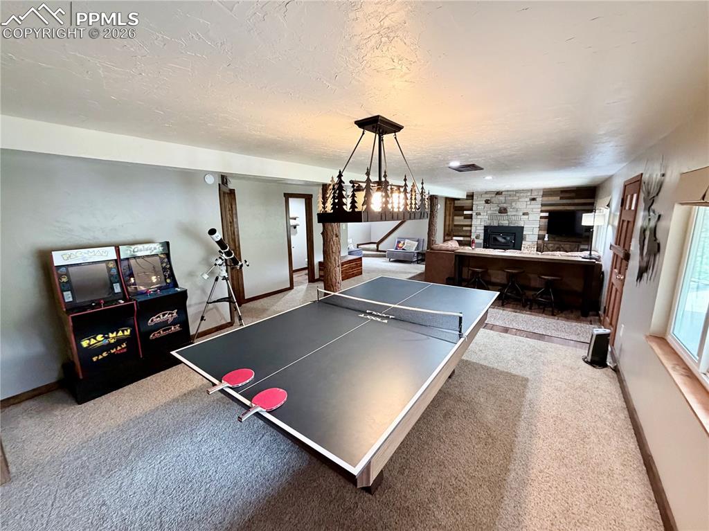 121 St Charles Drive Rye, CO 81069 - Photo 13 of 22 Playroom featuring a fireplace, a textured ceiling, and light carpet