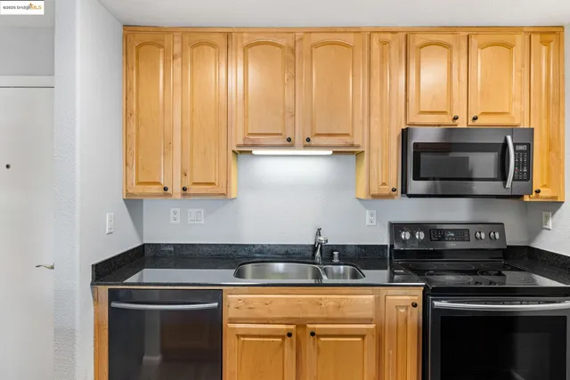 a kitchen with stainless steel appliances granite countertop a sink a stove and a microwave