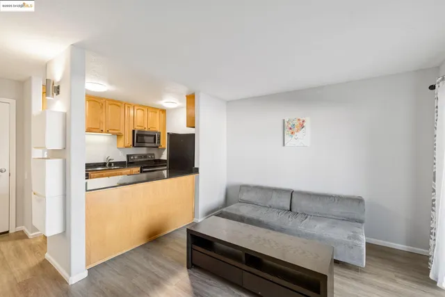 a living room with stainless steel appliances furniture a refrigerator and a kitchen island
