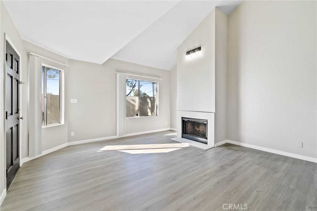 9013 Buckles Street Downey, CA 90241 - Photo 3 of 32 an empty room with wooden floor fireplace and windows