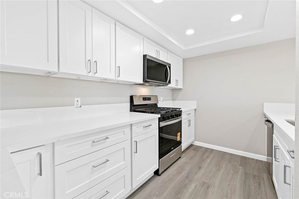 9013 Buckles Street Downey, CA 90241 - Photo 9 of 32 a kitchen with granite countertop white cabinets and stainless steel appliances
