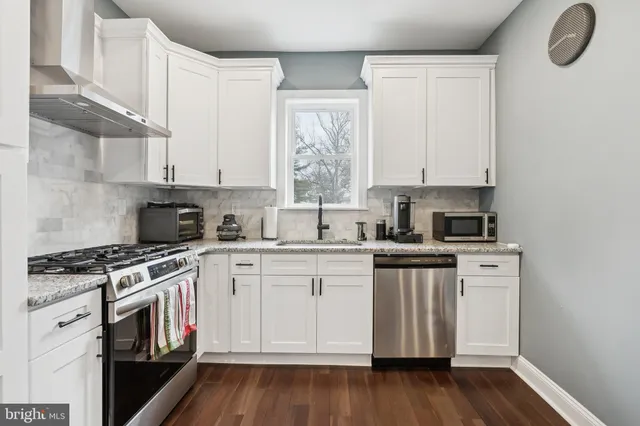 a kitchen with stainless steel appliances granite countertop a stove and white cabinets