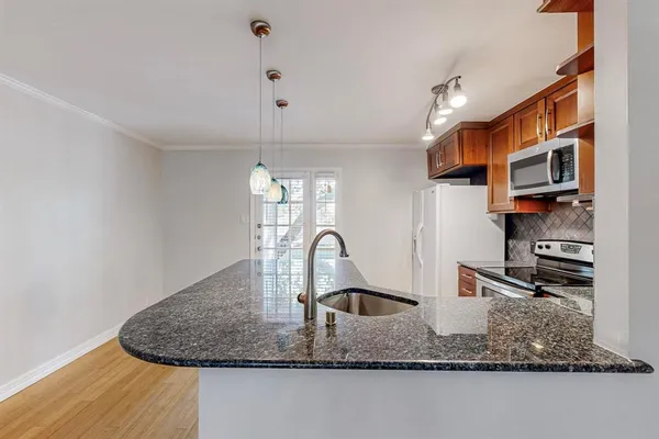 a kitchen with stainless steel appliances granite countertop a sink a stove and a refrigerator