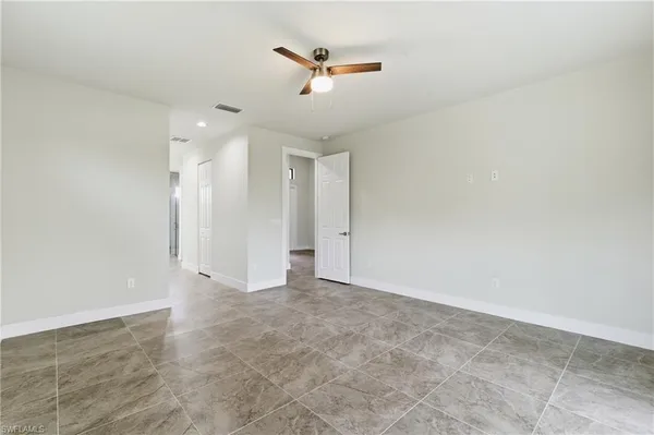 an empty room with ceiling fan and window