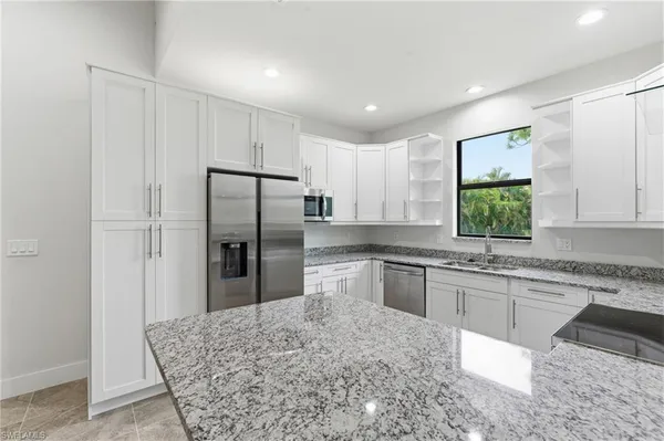 a kitchen with stainless steel appliances granite countertop a refrigerator sink and stove