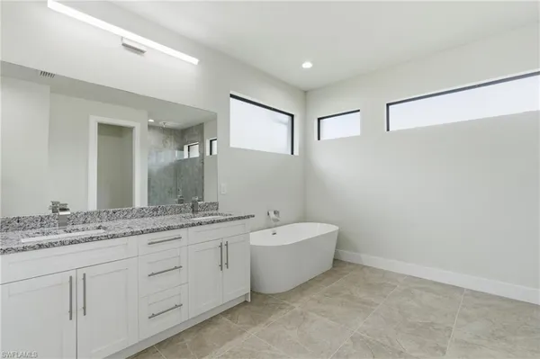 a spacious bathroom with a granite countertop sink mirror and bathtub