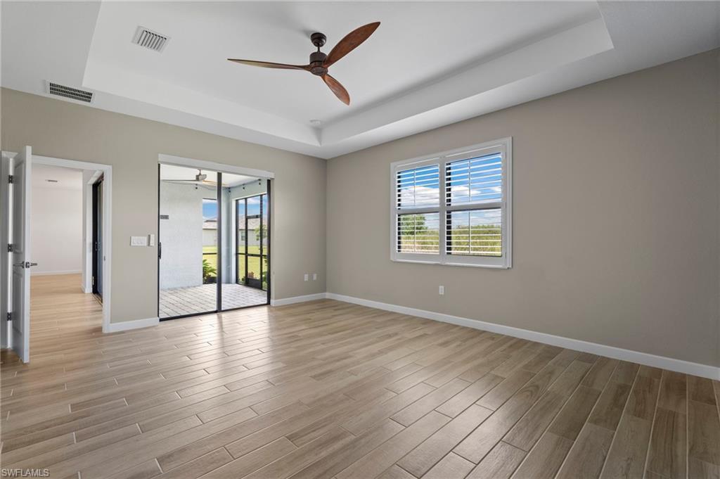 1779 Hagen Court Naples, FL 34120 - Photo 26 of 36 an empty room with wooden floor a ceiling fan and windows