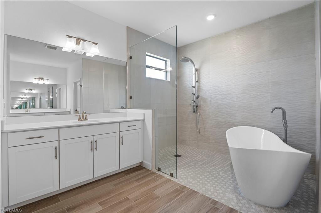 1779 Hagen Court Naples, FL 34120 - Photo 28 of 36 a spacious bathroom with a double vanity sink a mirror and a bathtub