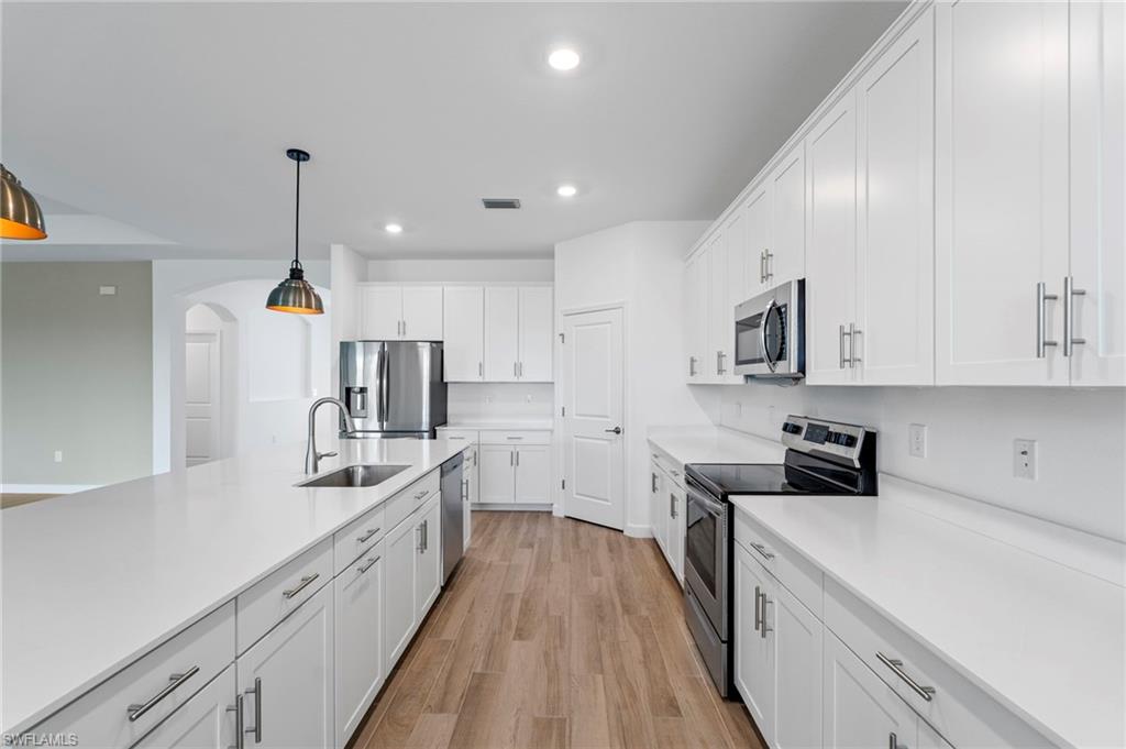 1779 Hagen Court Naples, FL 34120 - Photo 3 of 36 a kitchen with white cabinets and stainless steel appliances