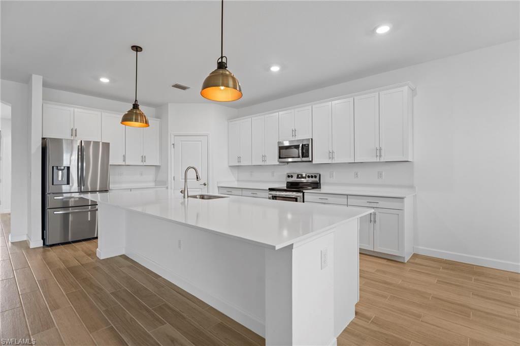 1779 Hagen Court Naples, FL 34120 - Photo 34 of 36 a kitchen with stainless steel appliances a stove a sink dishwasher a refrigerator and white cabinets with wooden floor