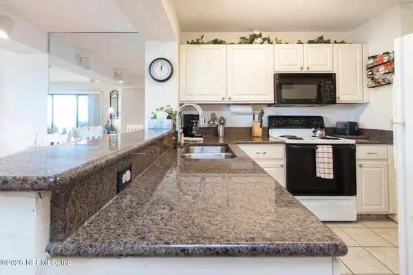 a large kitchen with granite countertop a stove a sink and a microwave