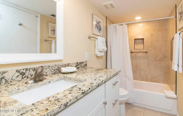a bathroom with a granite countertop sink and a mirror a bathtub