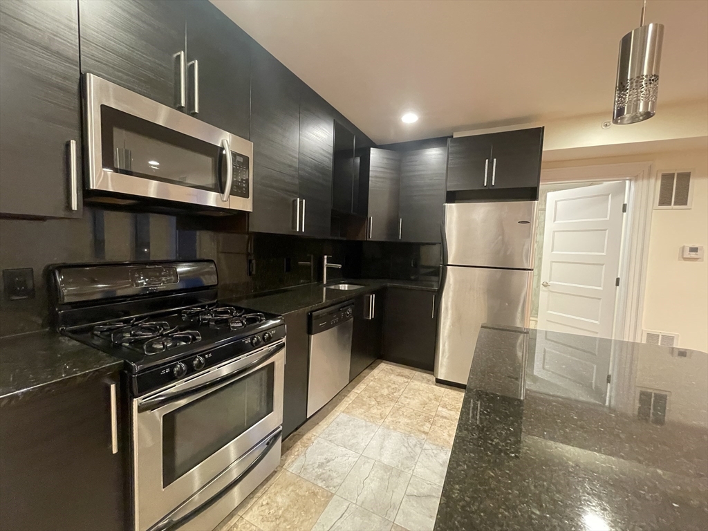 1616 Beacon Street, Unit 3 Brookline, MA 02446 - Photo 4 of 17 a kitchen with granite countertop a refrigerator and a stove top oven