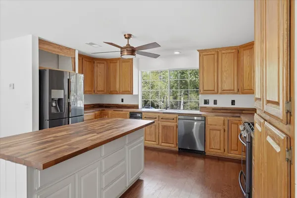 a kitchen with stainless steel appliances granite countertop a sink a stove a refrigerator a center island and cabinets