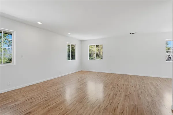 an empty room with wooden floor and windows