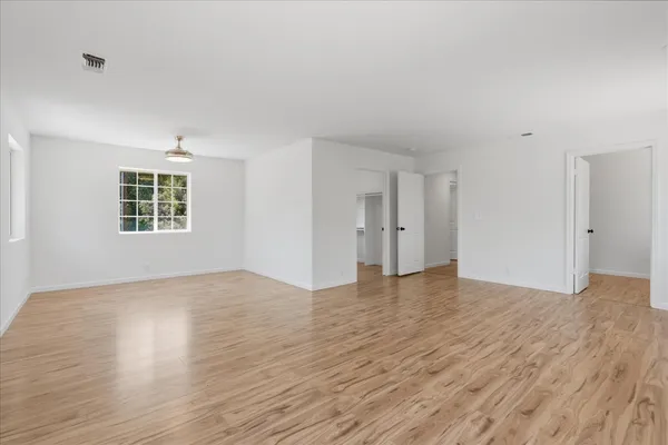 a view of an empty room with wooden floor and a window