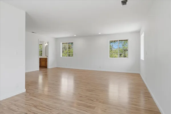 a view of an empty room with wooden floor and a window