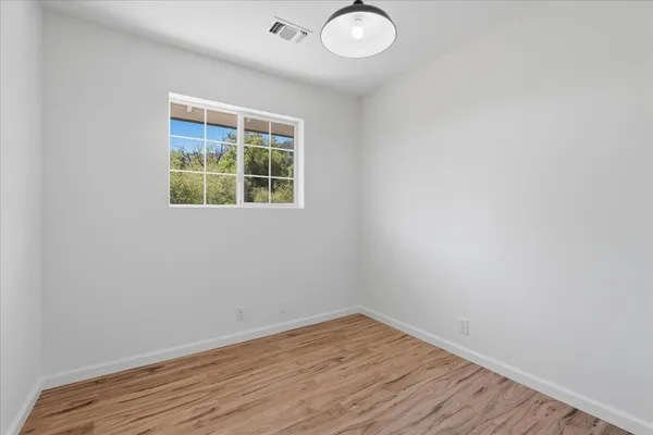 an empty room with wooden floor and windows