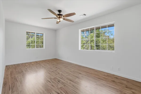 a view of an empty room with wooden floor and a window